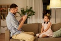 Father photographing daughter by cellphone at home