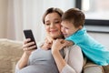 Pregnant mother and son with smartphone at home Royalty Free Stock Photo