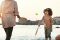 Family, tennis and girl play at beach, having fun and enjoying holiday or vacation together. Care, sunset and mother Royalty Free Stock Photo