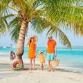 Family of three on beach under palm tree