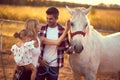 Family of three bonding with a white horse.  Fun on countryside, sunset golden hour. Freedom nature concept Royalty Free Stock Photo