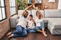 Family of three doing house shape with arms pointing thumb up to the side smiling happy with open mouth