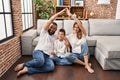 Family of three doing house shape with arms smiling with an idea or question pointing finger with happy face, number one Royalty Free Stock Photo