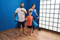 Family of three holding yoga mat pointing finger to one self smiling happy and proud