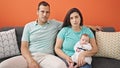 Family of three looking serious sitting on the sofa at home