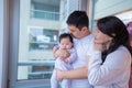 family of three, a man and two women, are hugging a baby