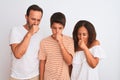 Family of three, mother, father and son standing over white isolated background feeling unwell and coughing as symptom for cold or