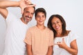 Family of three, mother, father and son standing over white isolated background smiling making frame with hands and fingers with