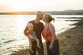 Family of three person is standing on sunset and sea backdrop Royalty Free Stock Photo