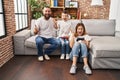 Family of three playing video game sitting on the sofa celebrating victory with happy smile and winner expression with raised Royalty Free Stock Photo