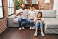 Family of three playing video game sitting on the sofa pointing finger to one self smiling happy and proud Royalty Free Stock Photo