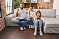 Family of three playing video game sitting on the sofa pointing thumb up to the side smiling happy with open mouth Royalty Free Stock Photo