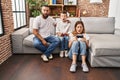 Family of three playing video game sitting on the sofa scared and amazed with open mouth for surprise, disbelief face Royalty Free Stock Photo