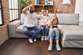 Family of three playing video game sitting on the sofa stressed and frustrated with hand on head, surprised and angry face Royalty Free Stock Photo