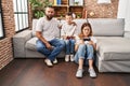 Family of three playing video game sitting on the sofa thinking attitude and sober expression looking self confident Royalty Free Stock Photo