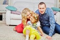 Family of three sits on carpet in light room,