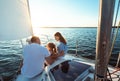 Family Of Three Sitting On Yacht Deck Sailing In Sea