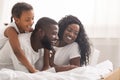 Family of three using laptop while lying on bed together Royalty Free Stock Photo