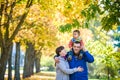 Family of three walks in the autumn park holding hands. happy father carrying son with maple leaves. Mother embrace her cute boy Royalty Free Stock Photo