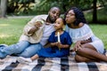 Family time, vacations, leisure together. Joyful African American famile with little kid girl blowing bubbles together