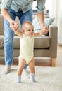 Father helping baby daughter with walking at home Royalty Free Stock Photo