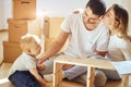 Family together at living room of new apartment assembling furniture, pile of moving boxes on background Royalty Free Stock Photo