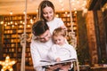 Family togetherness. Mom, dad and son reading story book together sitting on swing evening home. Family and Parenthood Concept. Royalty Free Stock Photo