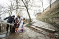 Family tourist look at map with three children, stand on wet path to an ancient medieval castle fortress in rain