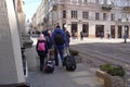 Family tourists dragging suitcases through the streets of a old center city. refugees with suitcases on the street of Lviv during