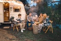 Family trailer travel.Children,brother sister,mom dad playing guitar,singing song at fire.Evening picnic in nature Royalty Free Stock Photo