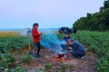 Family traveling and camping, twilight, cooking on the fire. Beautiful nature - field, forest and moon Royalty Free Stock Photo