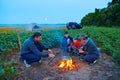 Family traveling and camping, twilight, cooking on the fire. Beautiful nature - field, forest and moon