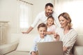 Family with two adorable children sitting together and using laptop at home Royalty Free Stock Photo