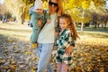 Family with children enjoying the walk in autumn park. Young mother with newborn baby and teen girl daughter relax in autumn fores Royalty Free Stock Photo