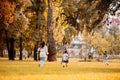 Family with two children flying a kite and running across grassy lawn