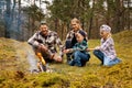 family frying sausages over a bonfire while camping in forest. family time, nature adventure