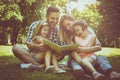 Family with two children in meadow reading book together Royalty Free Stock Photo