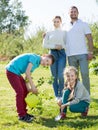 Family with two teenagers placing a new tree