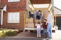 Family Unpacking Moving In Boxes From Removal Truck