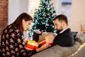 Family unwrapping Christmas present on sofa