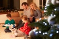 Family Unwrapping Gifts By Christmas Tree