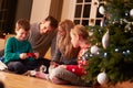 Family Unwrapping Gifts By Christmas Tree