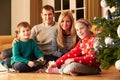 Family Unwrapping Gifts By Christmas Tree