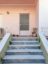 A family urban house entrance stairs to a small terrace, white door and pale pink wall.