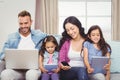 Family using modern technologies while sitting on sofa Royalty Free Stock Photo
