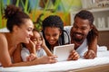 Family using tablet while lying together on bed Royalty Free Stock Photo