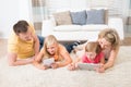 Family using tablets lying on carpet