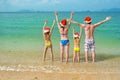 Family vacation on Christmas and New Year holidays, happy parents and children in santa hats have fun on beach Royalty Free Stock Photo