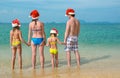 Family vacation on Christmas and New Year holidays, happy parents and children in santa hats have fun on beach Royalty Free Stock Photo