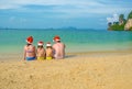 Family vacation on Christmas and New Year holidays, happy parents and children in santa hats have fun on beach Royalty Free Stock Photo